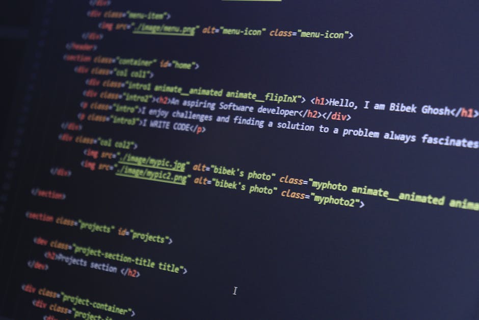 A close-up view of a person using a laptop on a wooden desk, displaying lines of code in a text editor with colorful syntax highlighting. The individual's right hand, wearing a black watch on the wris
